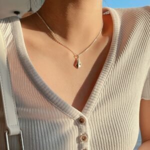 A silver geometric pendant necklace with modern minimalist design is on model's neck