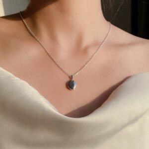 model wearing customised silver locket necklace to hold memories with the photos placed inside the locket yet being elegance to style with the white dress