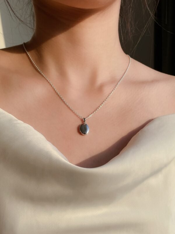 model wearing customised silver locket necklace to hold memories with the photos placed inside the locket yet being elegance to style with the white dress